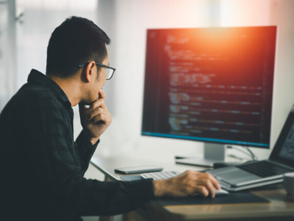 Man working on laptop for software company that provides dedicated IT solutions