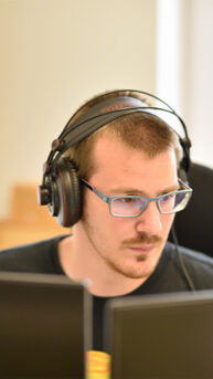 i4b team member with headphones behind the desk working on software for the future of electric vehicles
